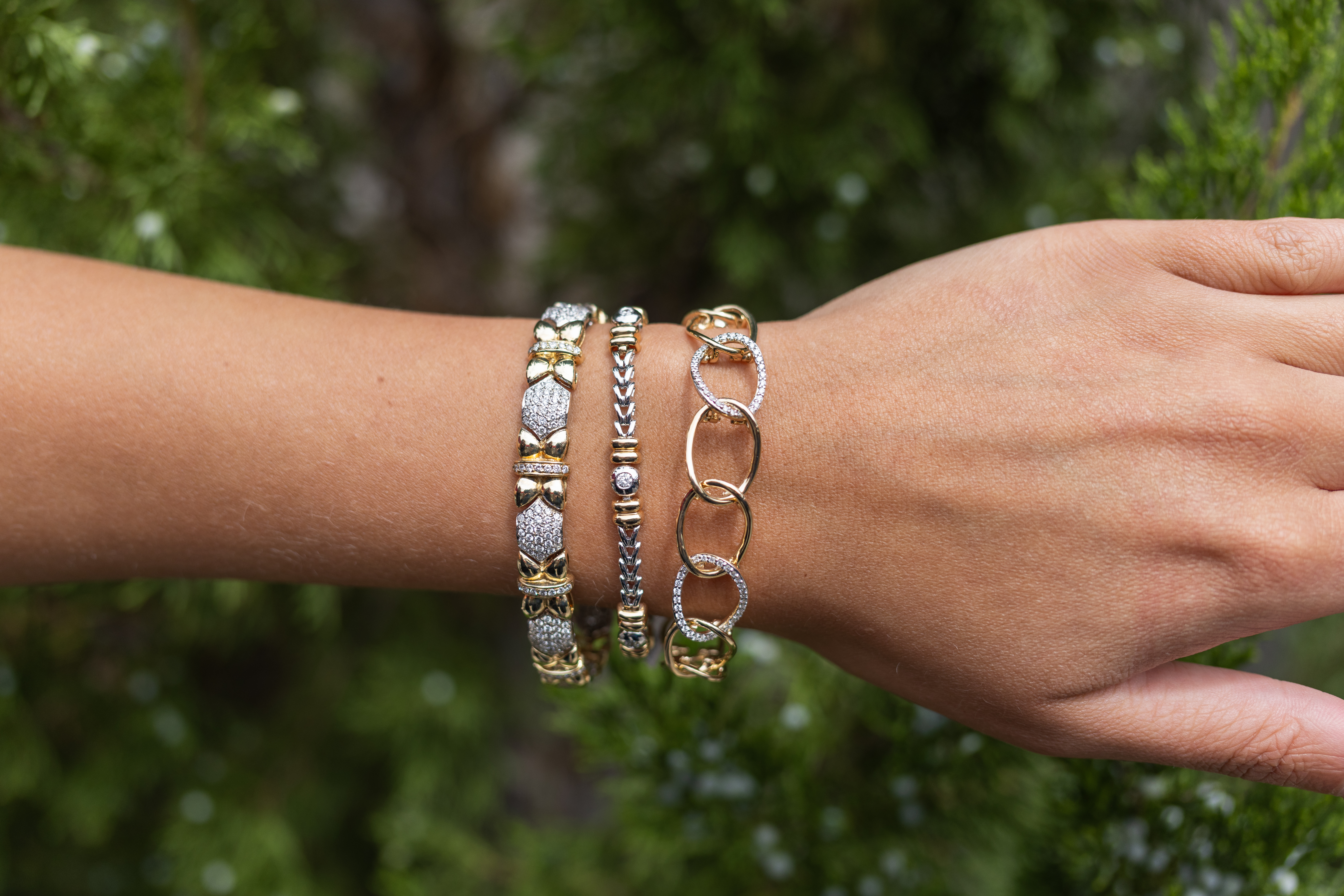 Gold bracelets with pearls and charms on a wrist.