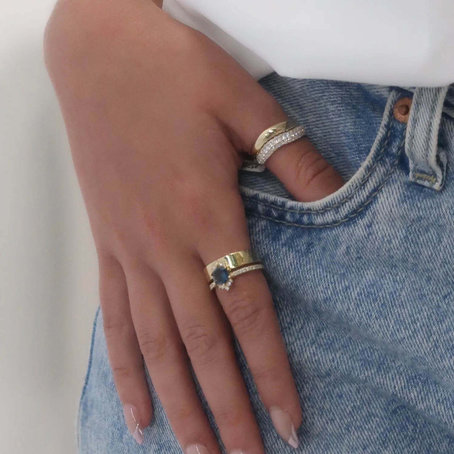 Two elegant gold rings with colorful stones displayed on a decorative stone.