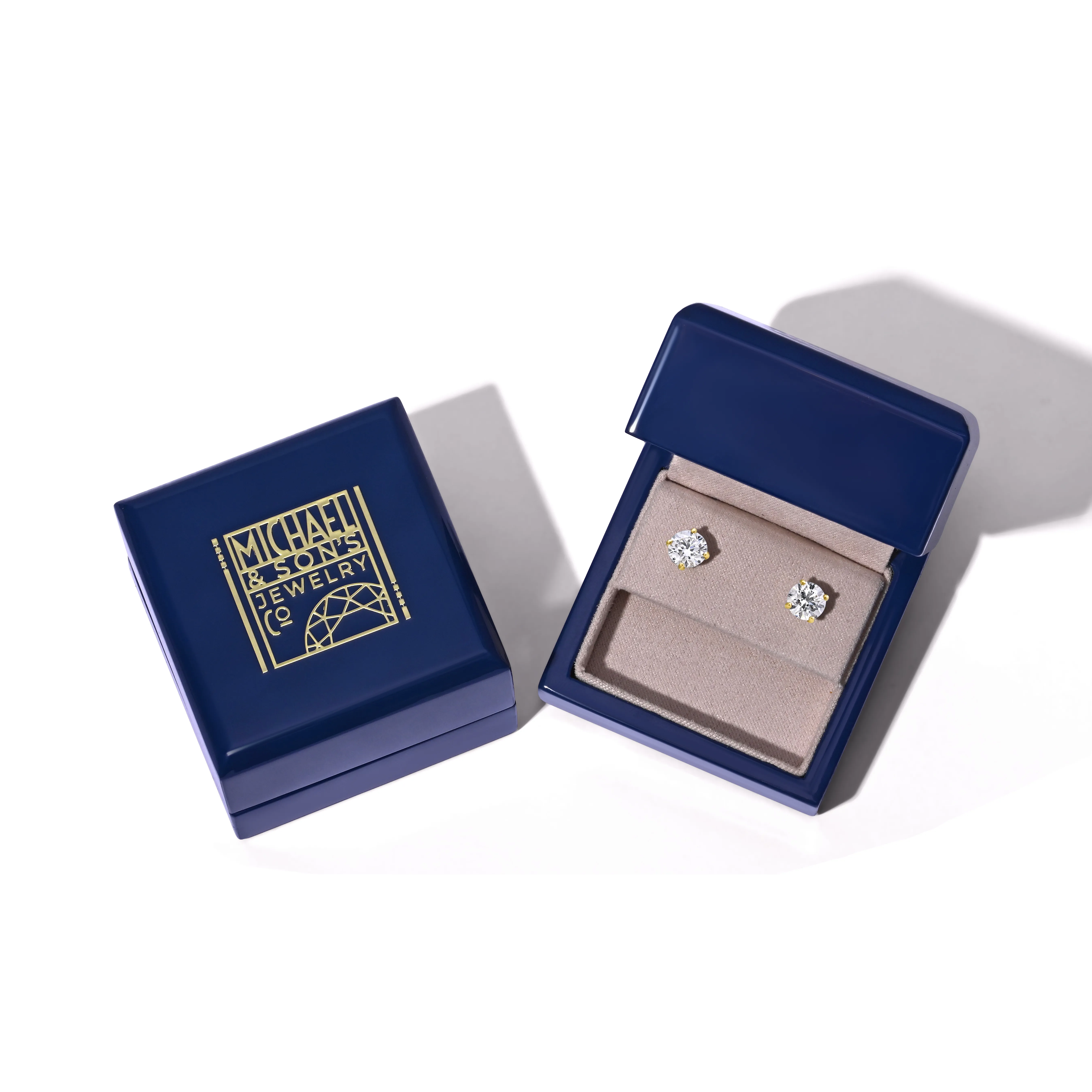 Three elegant rings displayed on a green stone, featuring a diamond engagement ring and two wedding bands.