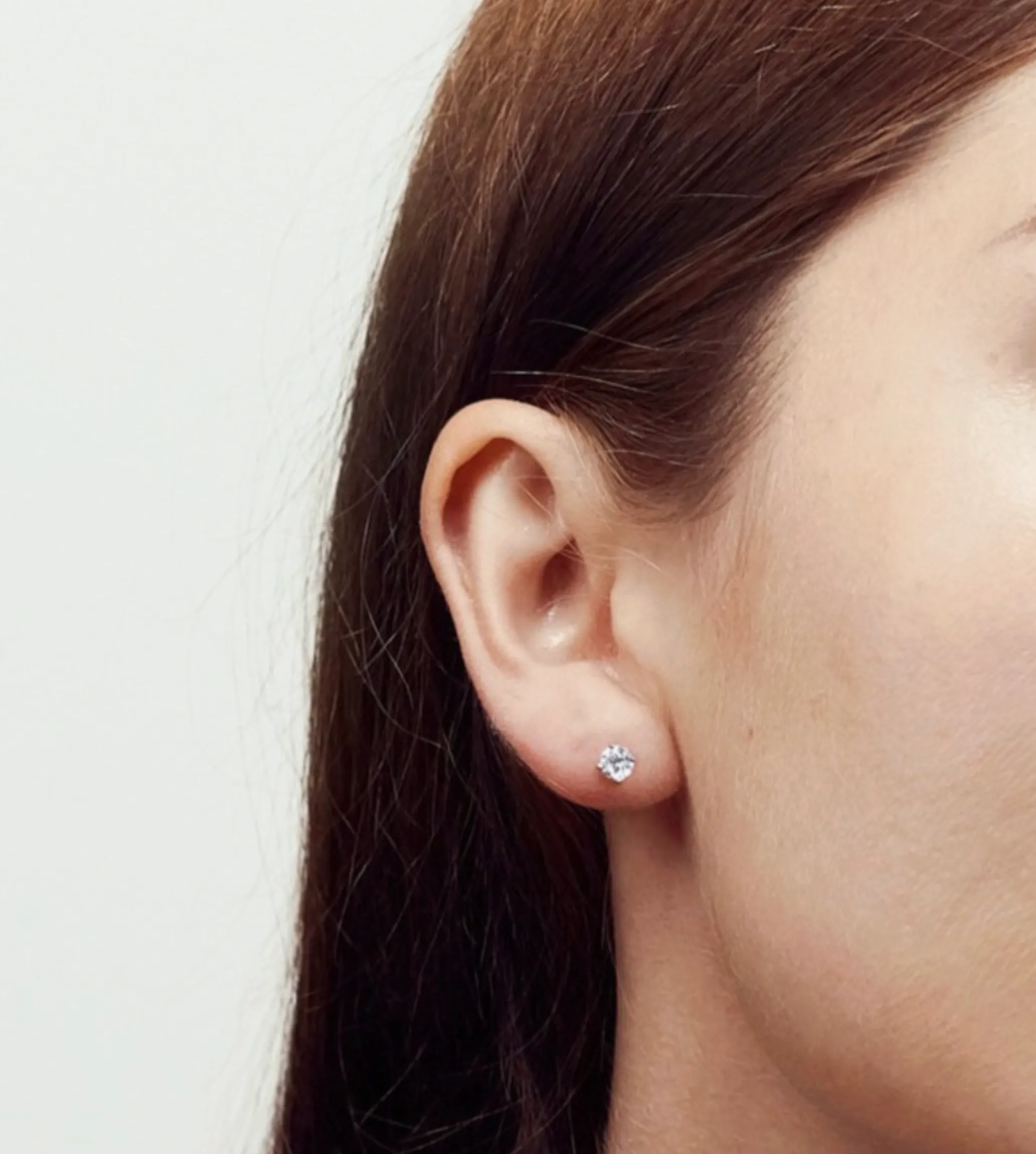 Woman wearing single diamond stud in the left ear. 