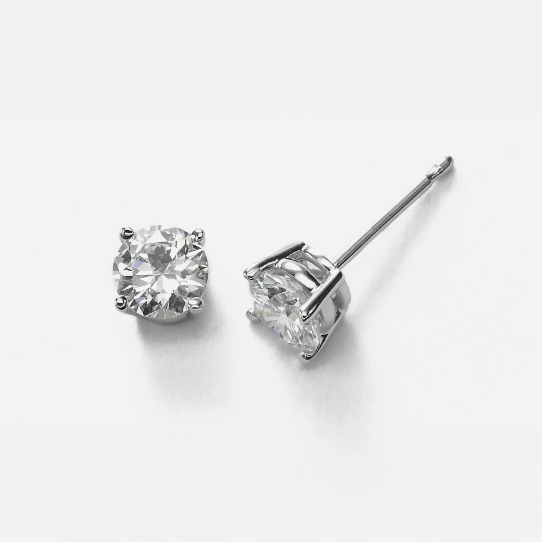 Sparkling diamond stud earrings on a white background, showcasing a classic and elegant design.