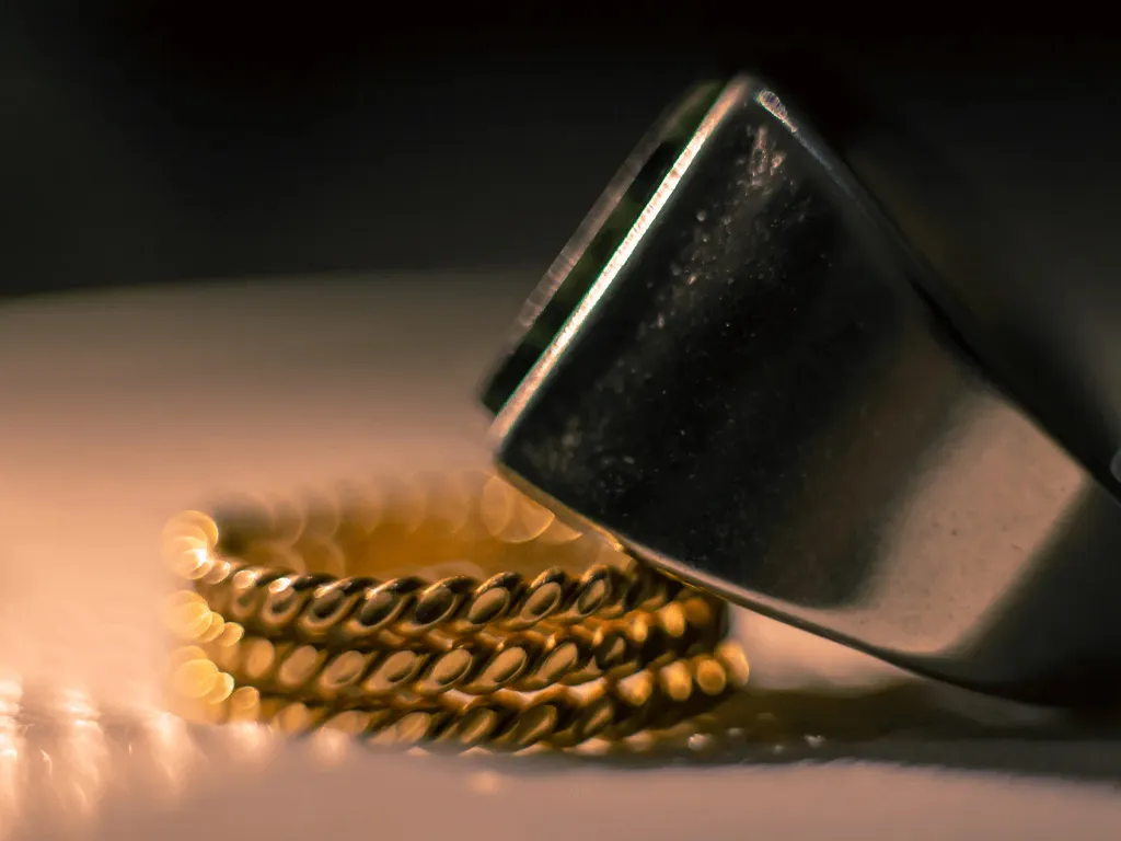 Close-up of a gold ring and a silver tool, showcasing jewelry craftsmanship.