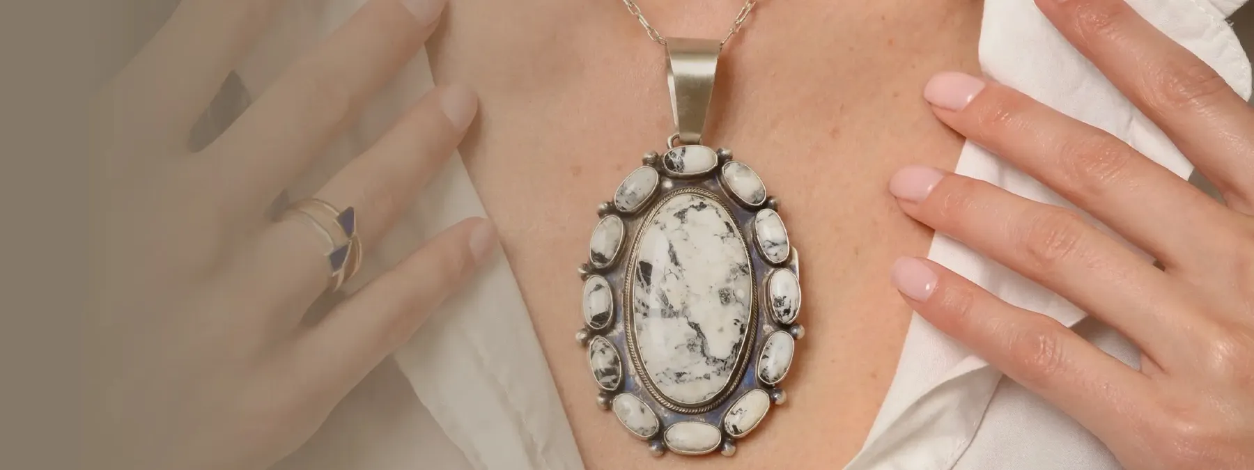 Close-up of a woman wearing a large, ornate pendant necklace with a unique stone design.