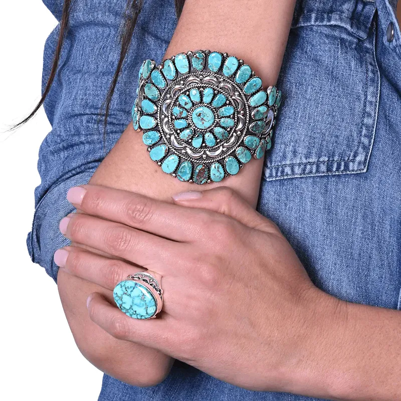 Turquoise jewelry featuring a bold cuff bracelet and ring, showcased on a model's hand.