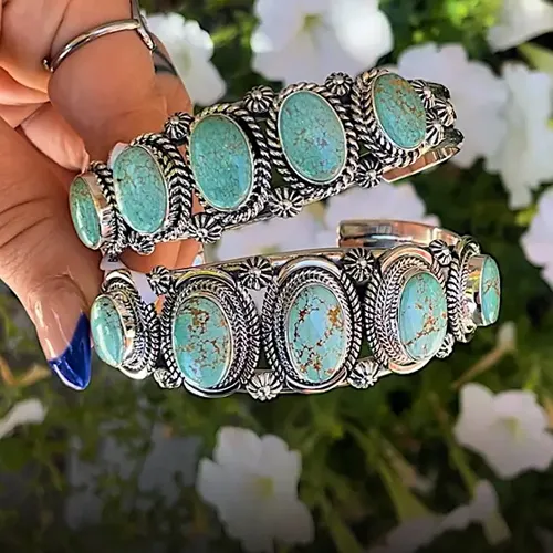 Turquoise cuff bracelets with intricate silver detailing, held in hand.