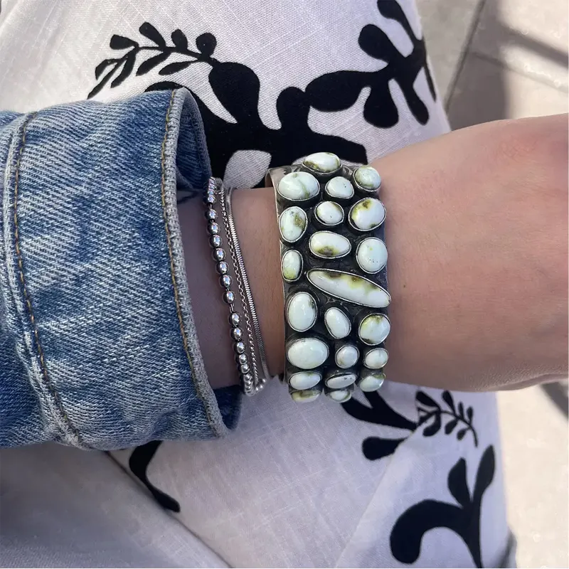 Stylish wrist adorned with a chunky turquoise and silver bracelet, paired with delicate silver bangles.