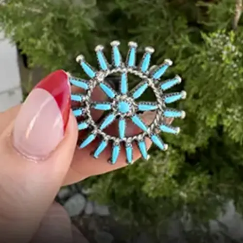 Turquoise pin with silver accents held in hand, promoting Michael & Son's Jewelers.