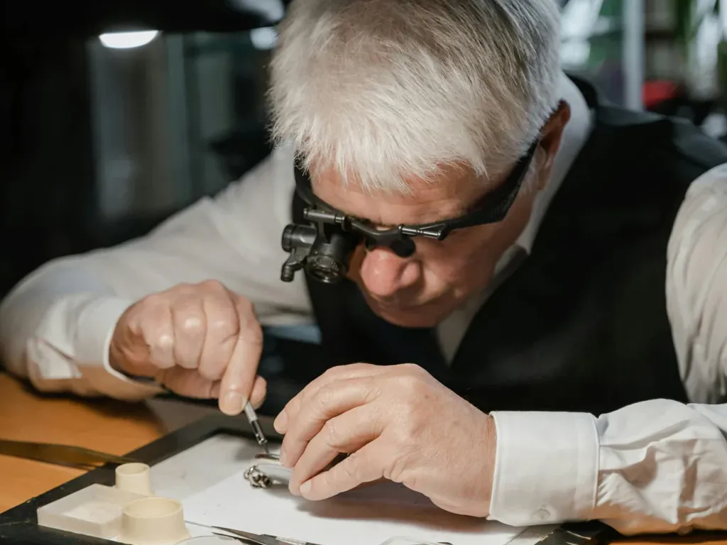 Jeweler repairing a watch with magnifying glasses, focused on intricate details