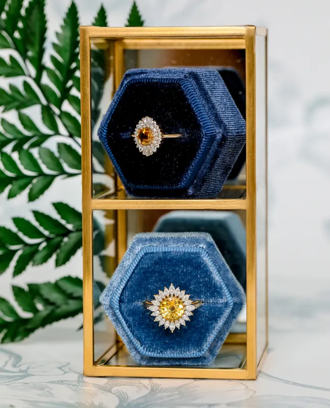 Elegant hexagonal ring boxes displaying a diamond ring and a yellow gemstone ring.