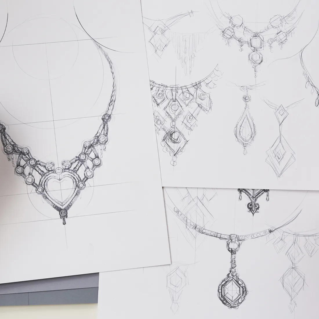 Sketches of intricate jewelry designs, including necklaces with heart and diamond shapes.