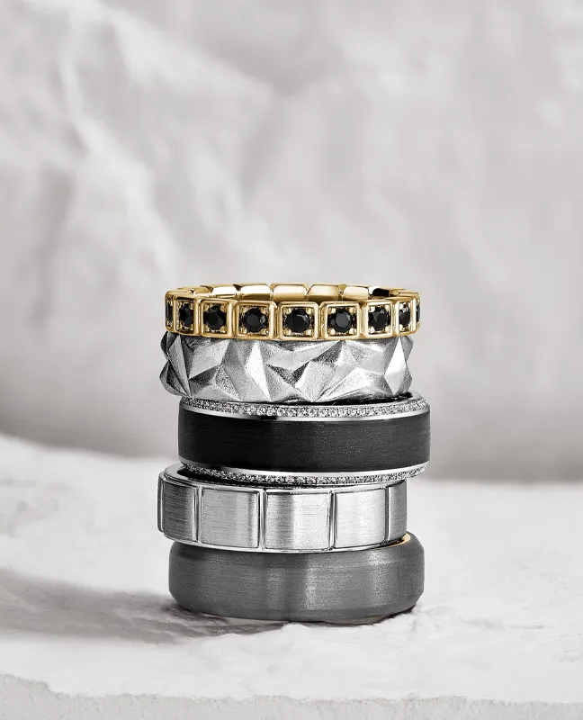 A stack of men's bands in gold, black and tungsten
