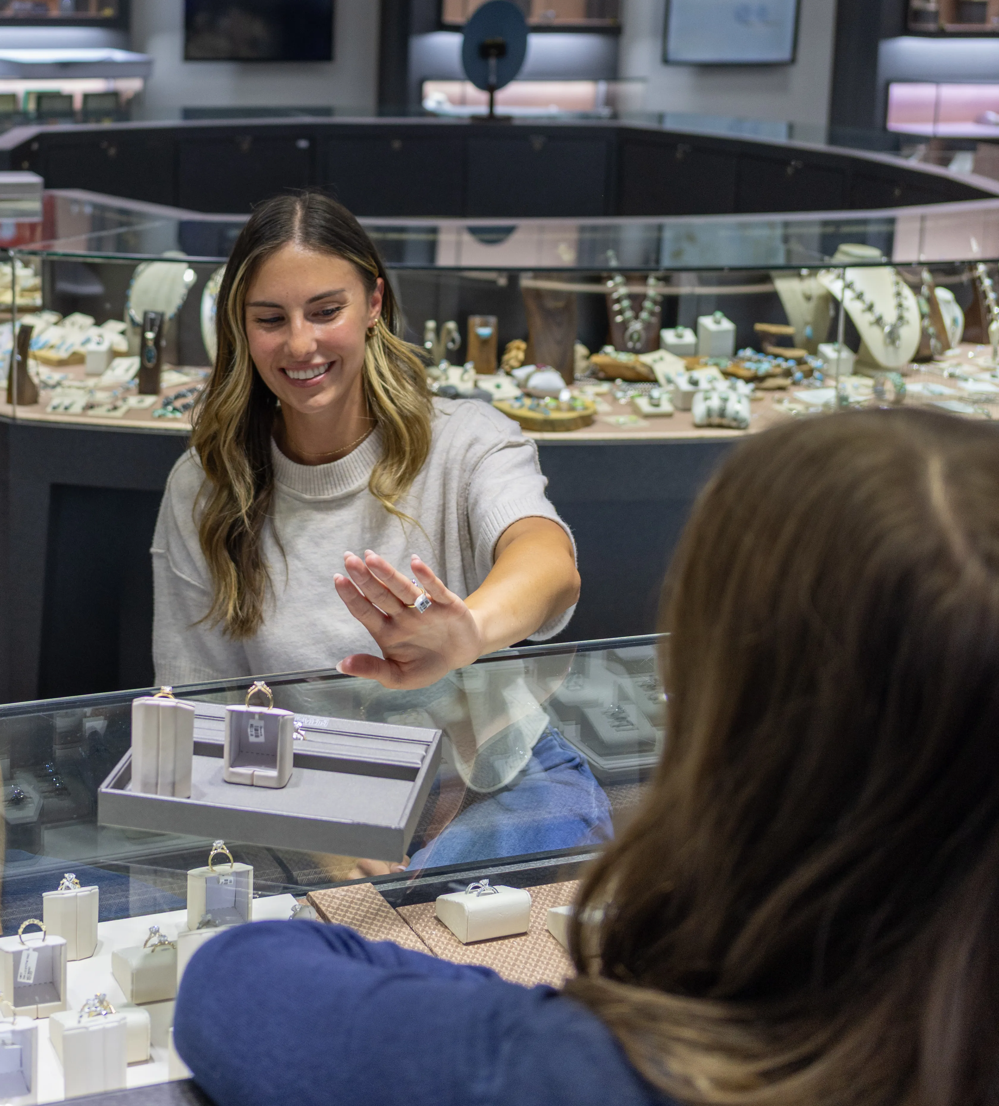 A hand drawing a detailed jewelry design on paper, showcasing intricate patterns and measurements.