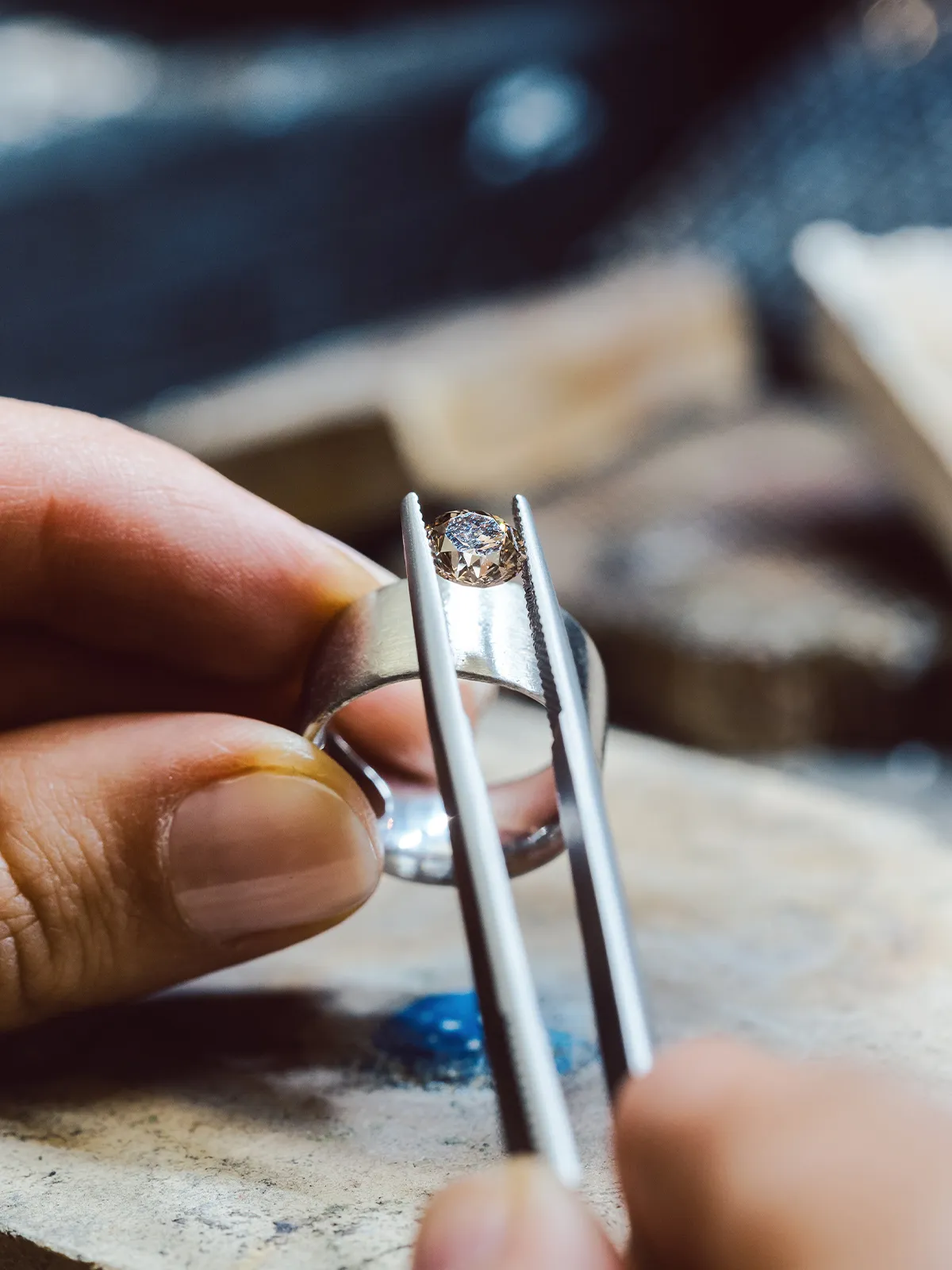 Jeweler setting a gemstone in a silver ring using tweezers.