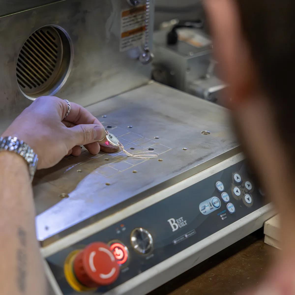 A person engraving jewelry with a laser machine.