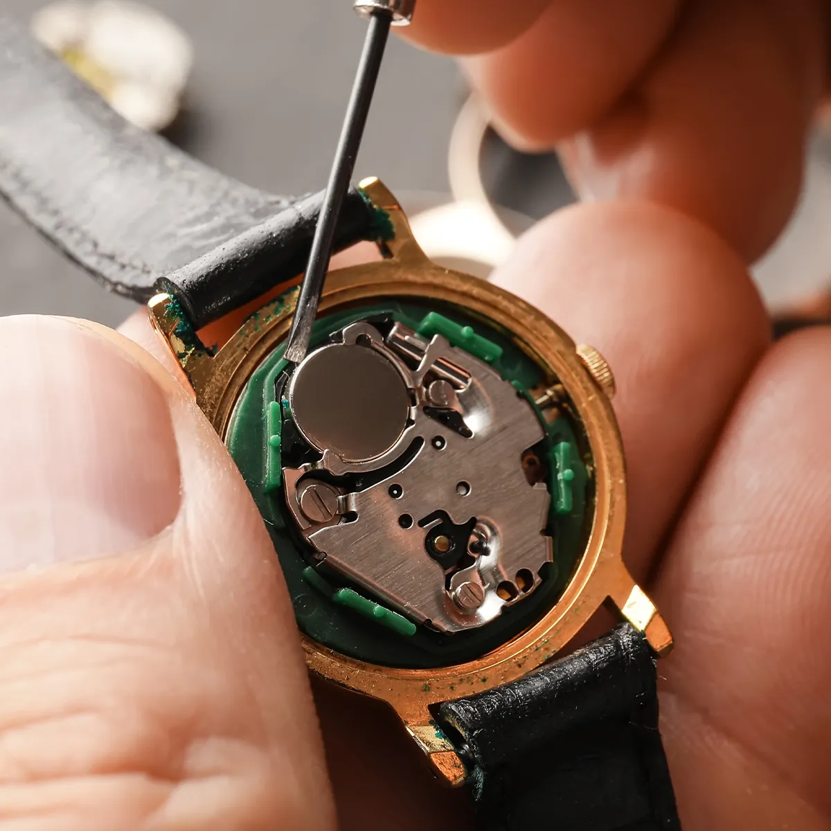 Watch mechanism being repaired with a small tool, close-up view.