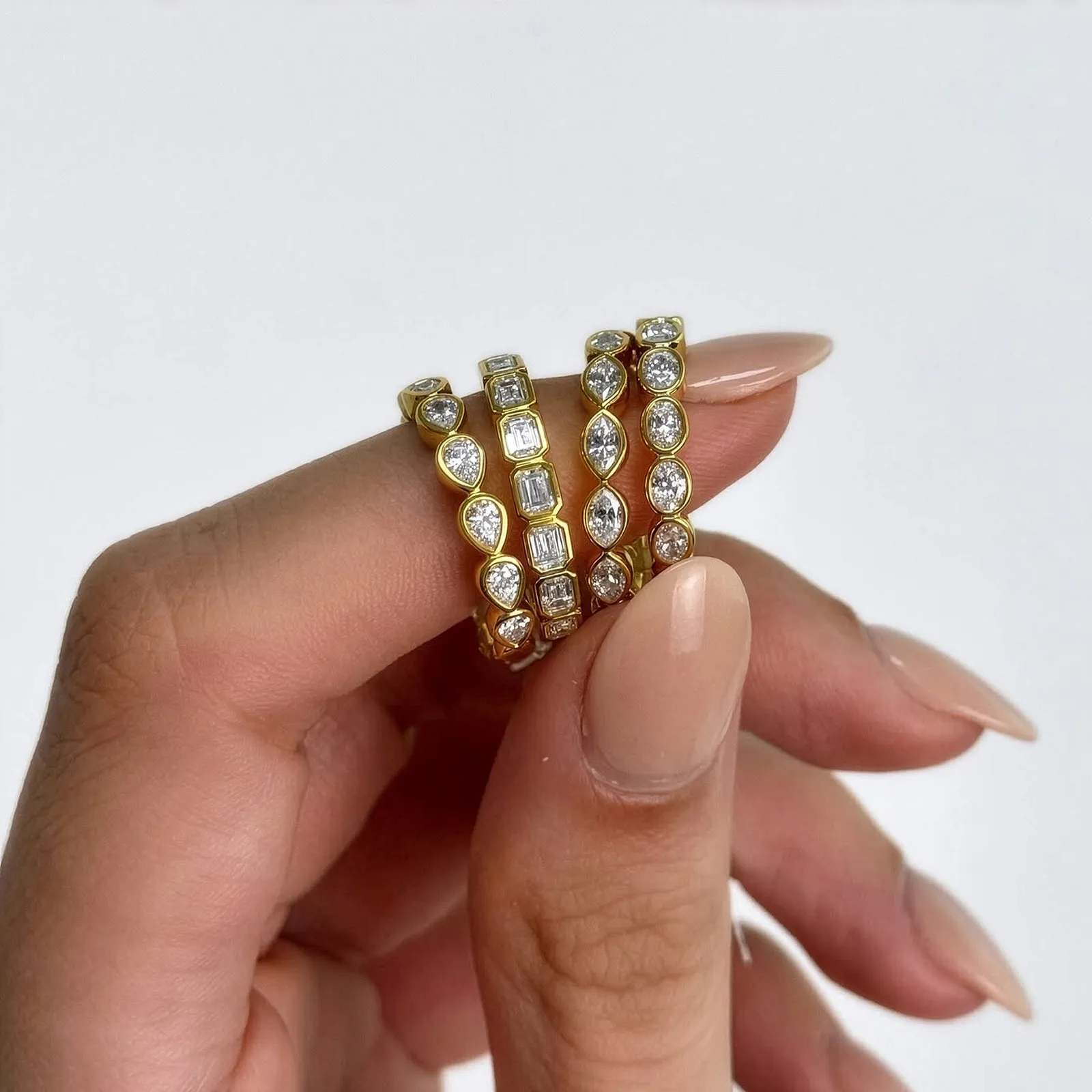 Three gold diamond rings held between fingers. Shop diamond favorites at Midtown Jewelers.