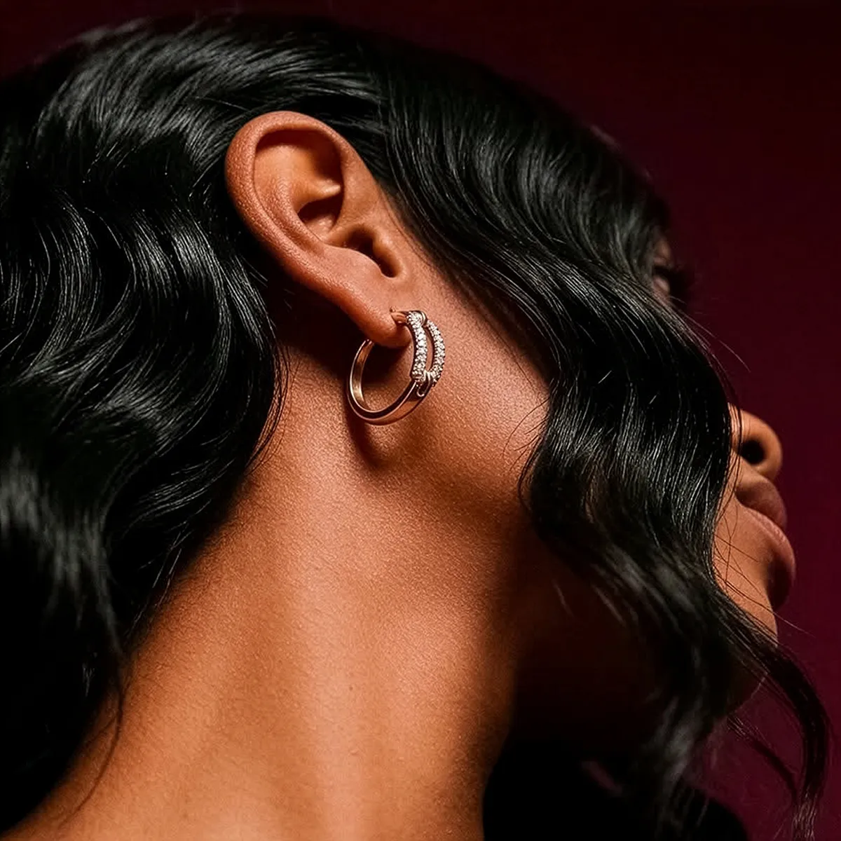 Close-up of an ear with a gold hoop earring and diamonds. Explore earrings at Midtown Jewelers.