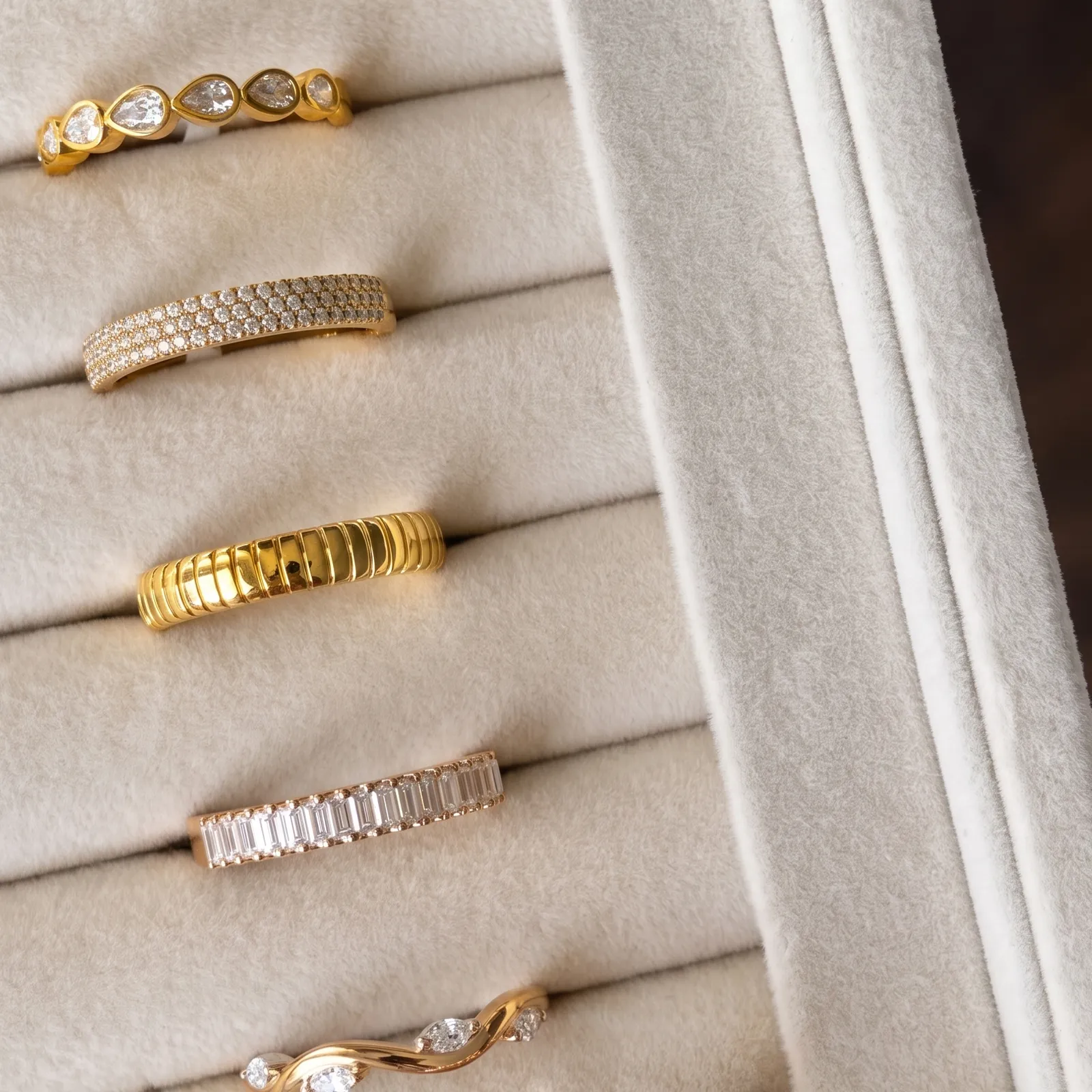 Elegant gold and diamond rings displayed in a jewelry box. Shop Now.