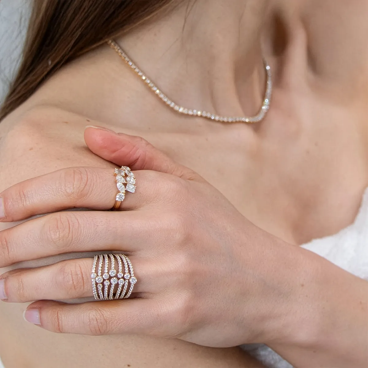 A woman wearing diamond rings and a necklace, showcasing fine jewelry.
