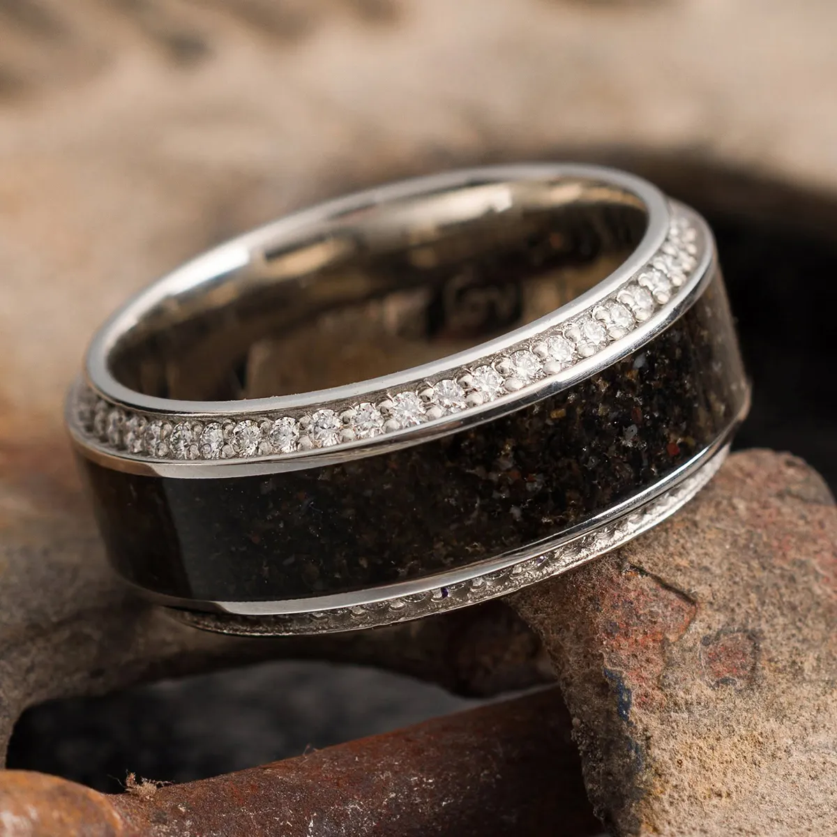 Elegant ring with dark inlay and diamond accents on a textured surface.