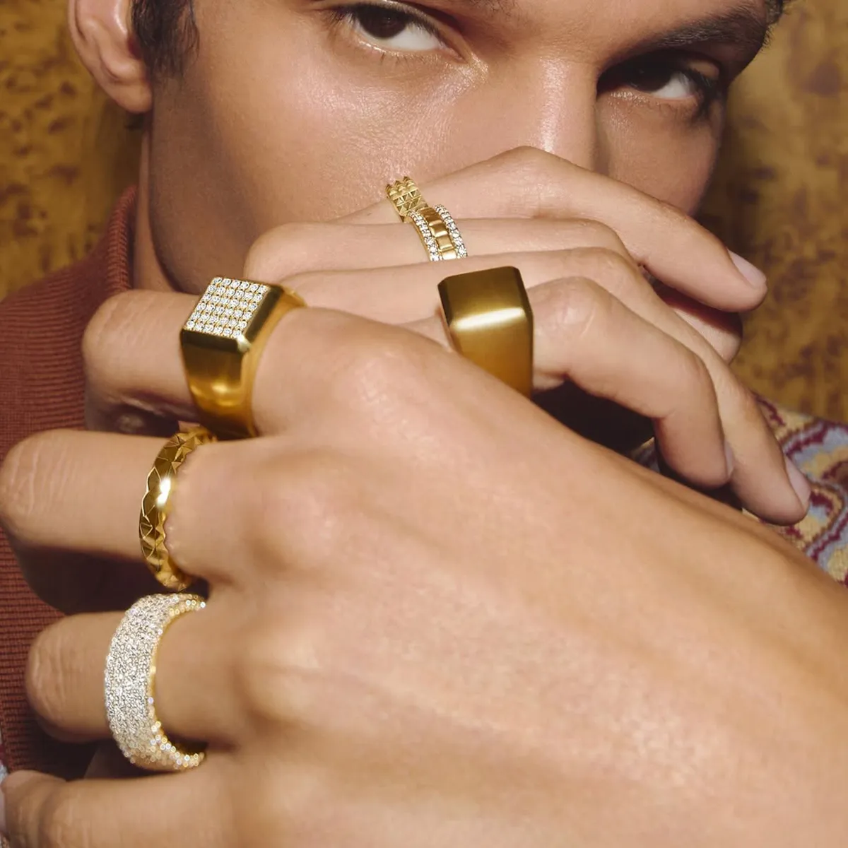 Close-up of a person wearing multiple gold and diamond rings on their fingers.