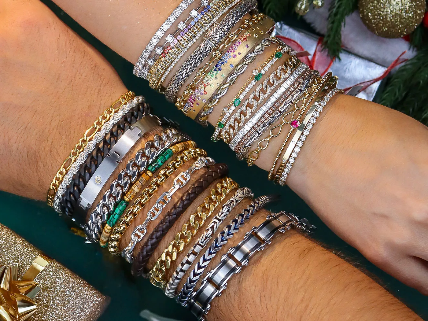 Two wrists adorned with a variety of colorful bracelets, showcasing gemstones and intricate designs. Click to shop the collectio