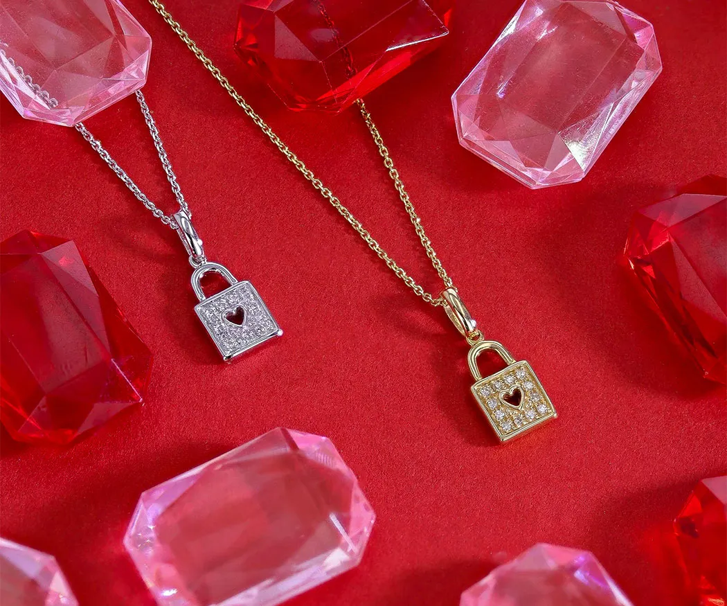 Two heart lock necklaces in silver and gold, surrounded by red and pink gems on a red background. Shop at Miner's Den Jewelers.