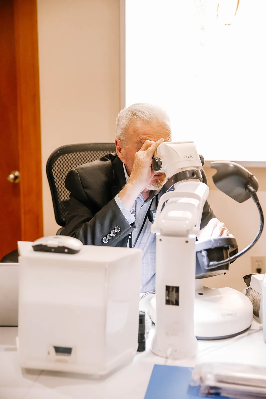 A person examining a gemstone with a magnifying glass for jewelry appraisal.
