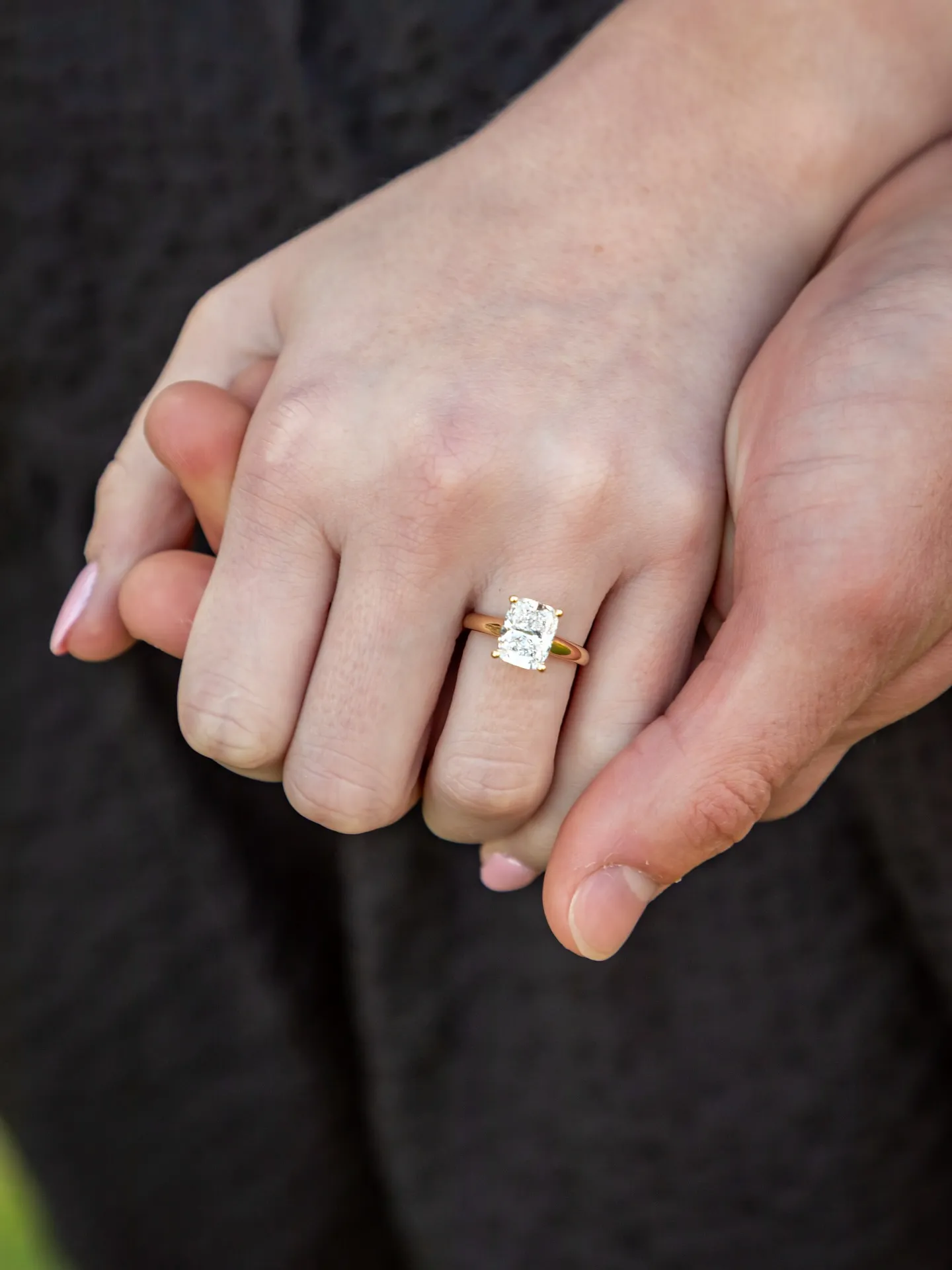 Close-up of hands holding, showcasing an engagement ring.