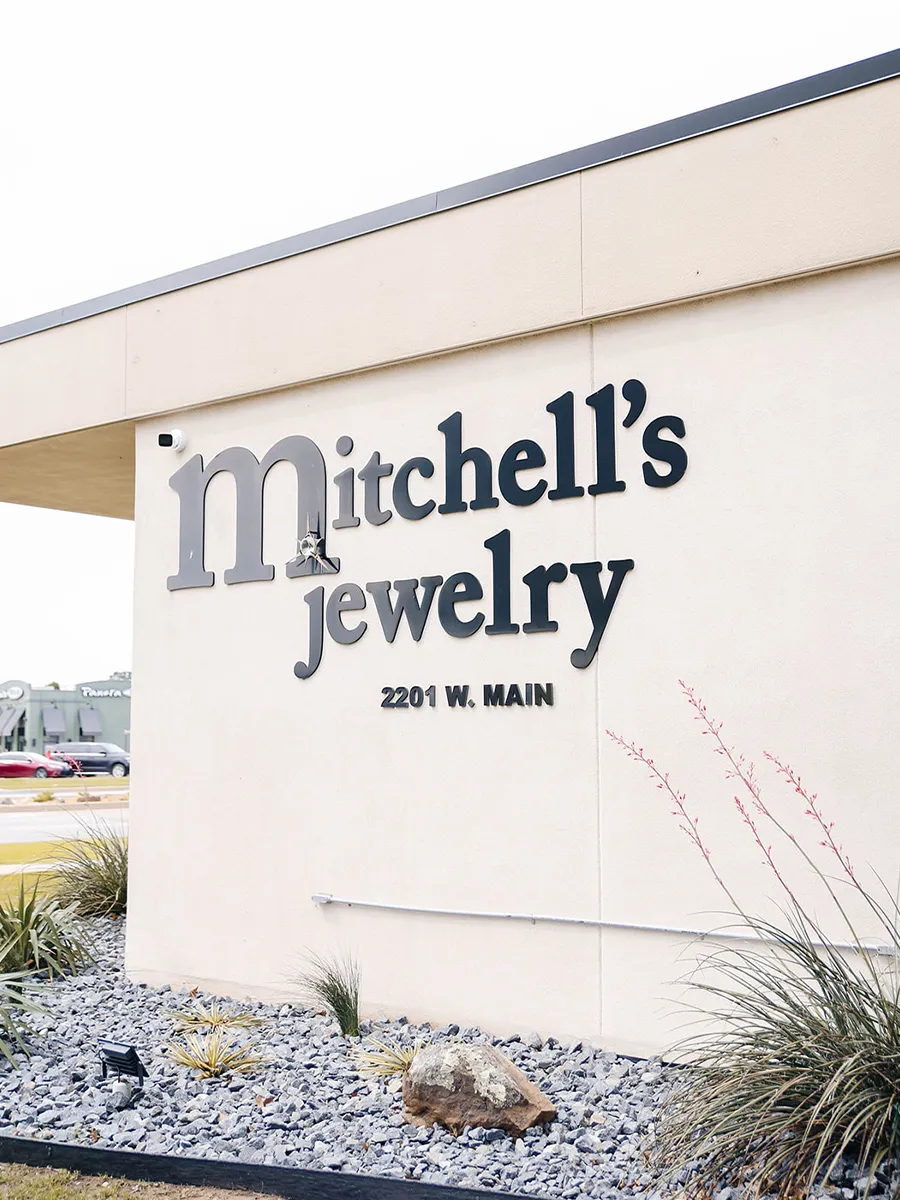 Sign for Mitchell's Jewelry at 2201 W. Main, Norman, with landscaped rocks and plants.