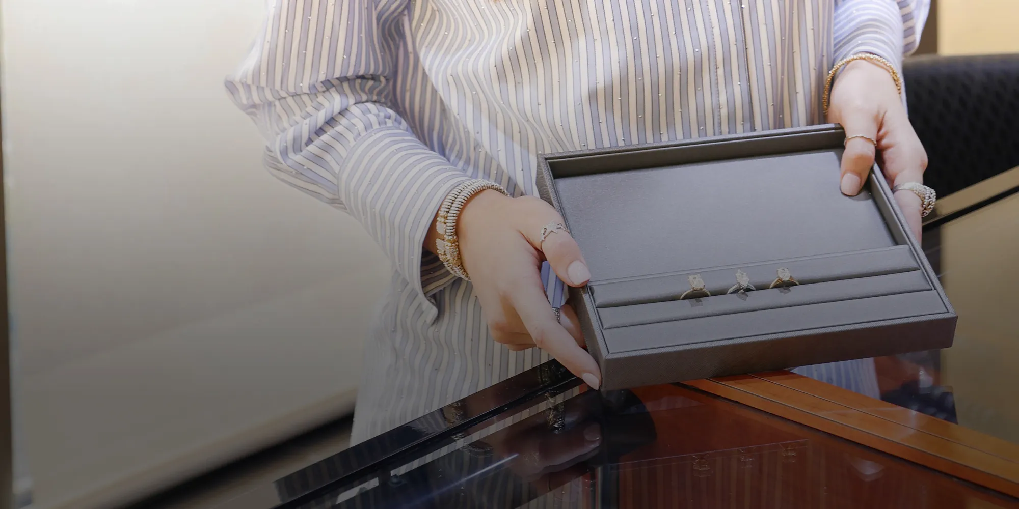 Person holding a tray with rings at a jewelry store. Book a Consultation.