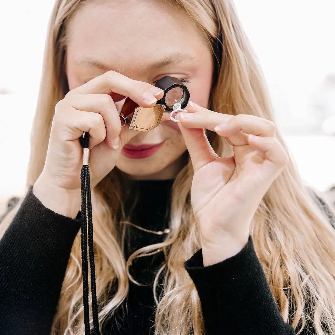 A person placing a gold ring with a large gemstone on their finger.