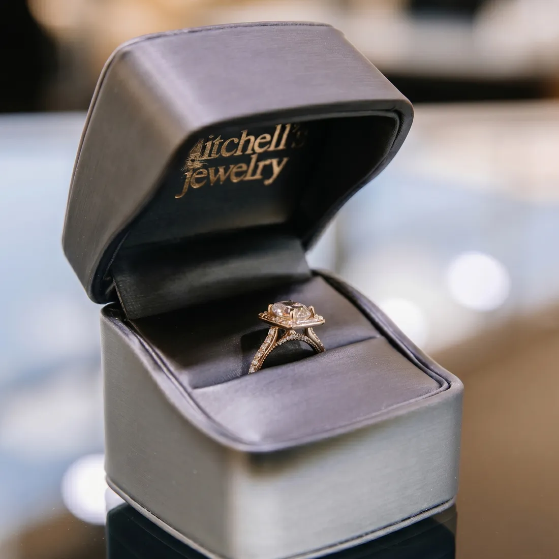 A diamond ring in an open black jewelry box from Mitchell's Jewelry.