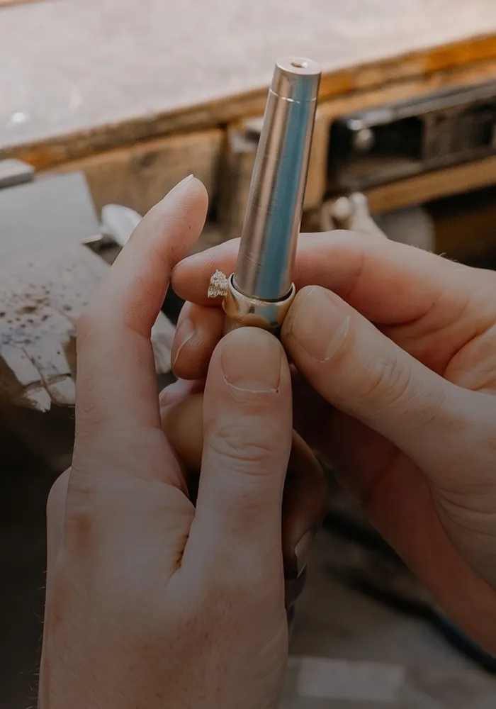 Jeweler working on a ring at a workbench. Book an Appointment.