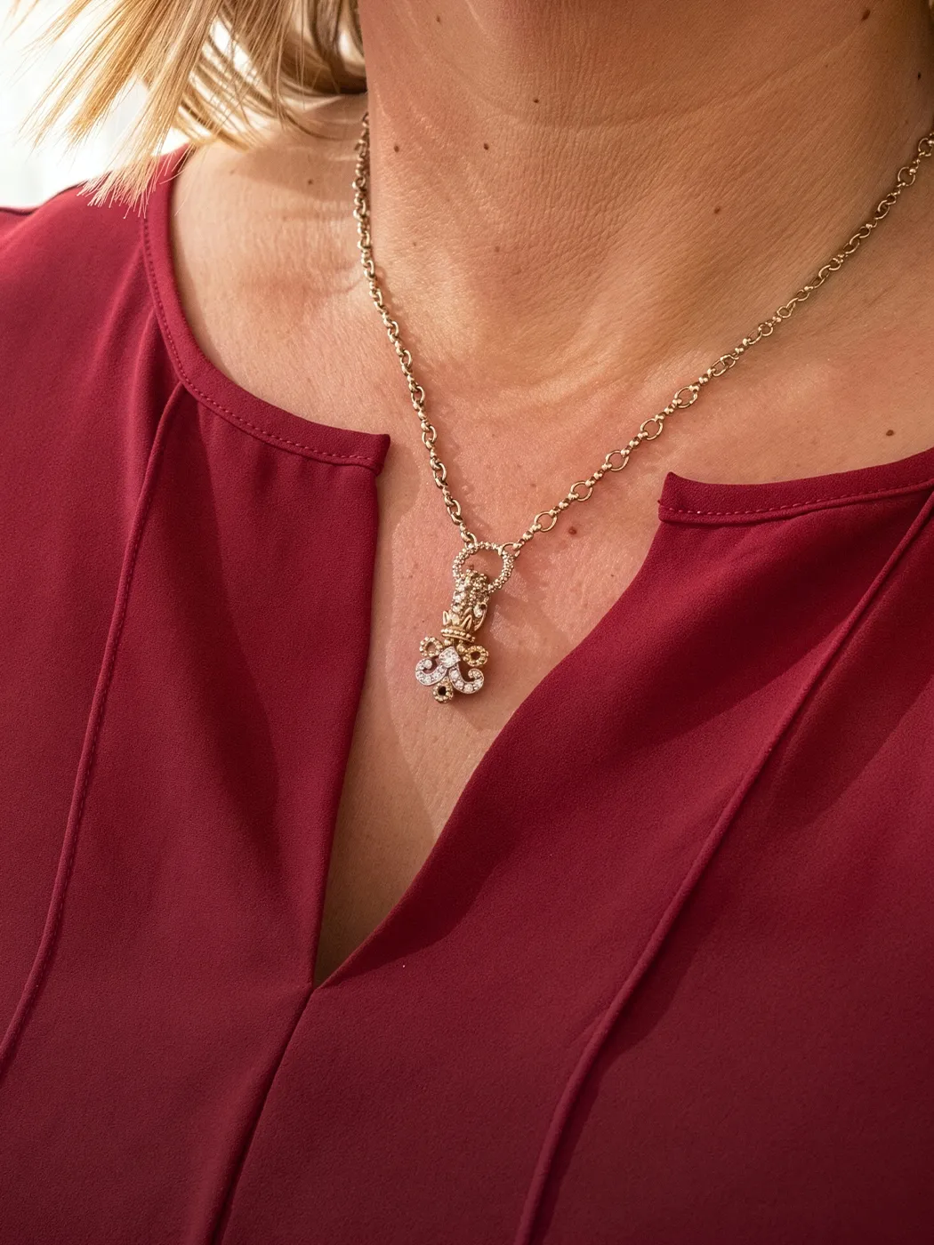 Gold chain necklace with diamond pendant worn over a red blouse.