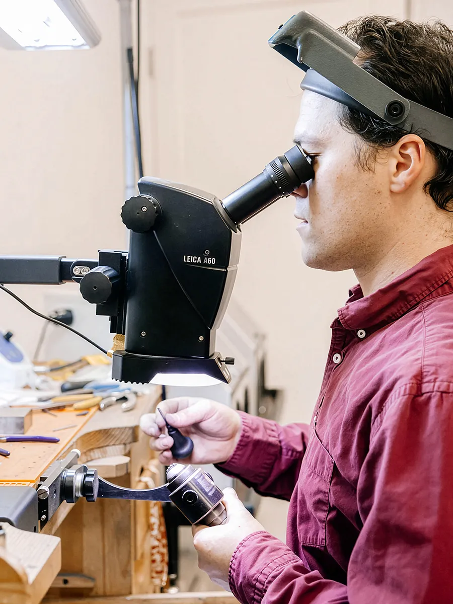 Jeweler using a microscope for detailed work at a bench in Mitchell's Jewelry.