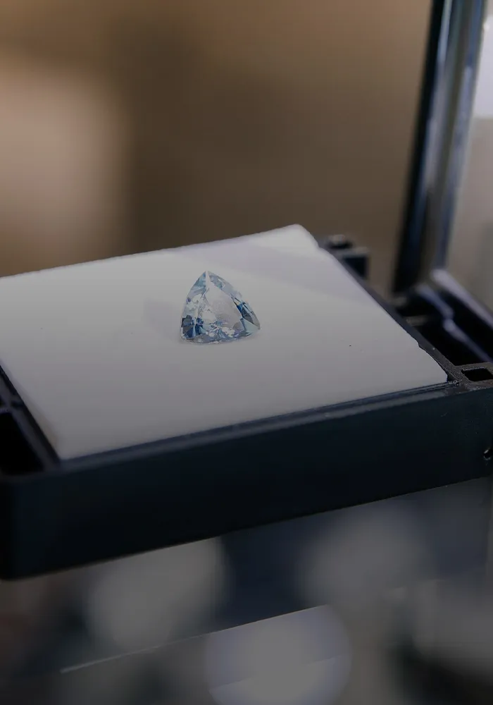 A single diamond displayed on a white cushion in a jewelry store setting.