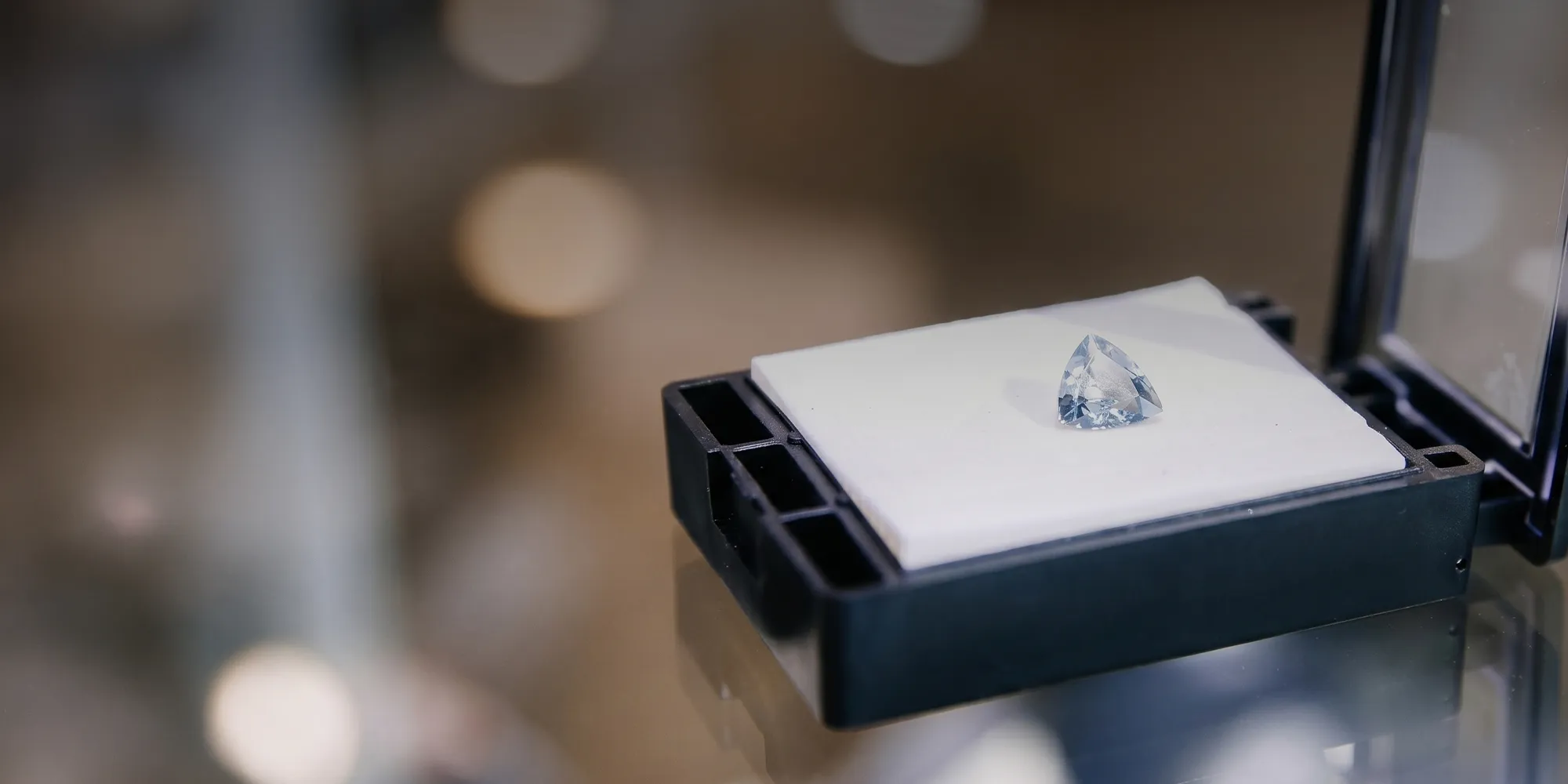 A single diamond displayed on a white cushion in a jewelry store setting.