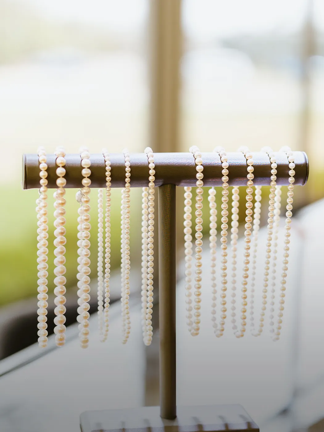 Pearl necklaces hanging on a display stand in a jewelry store.