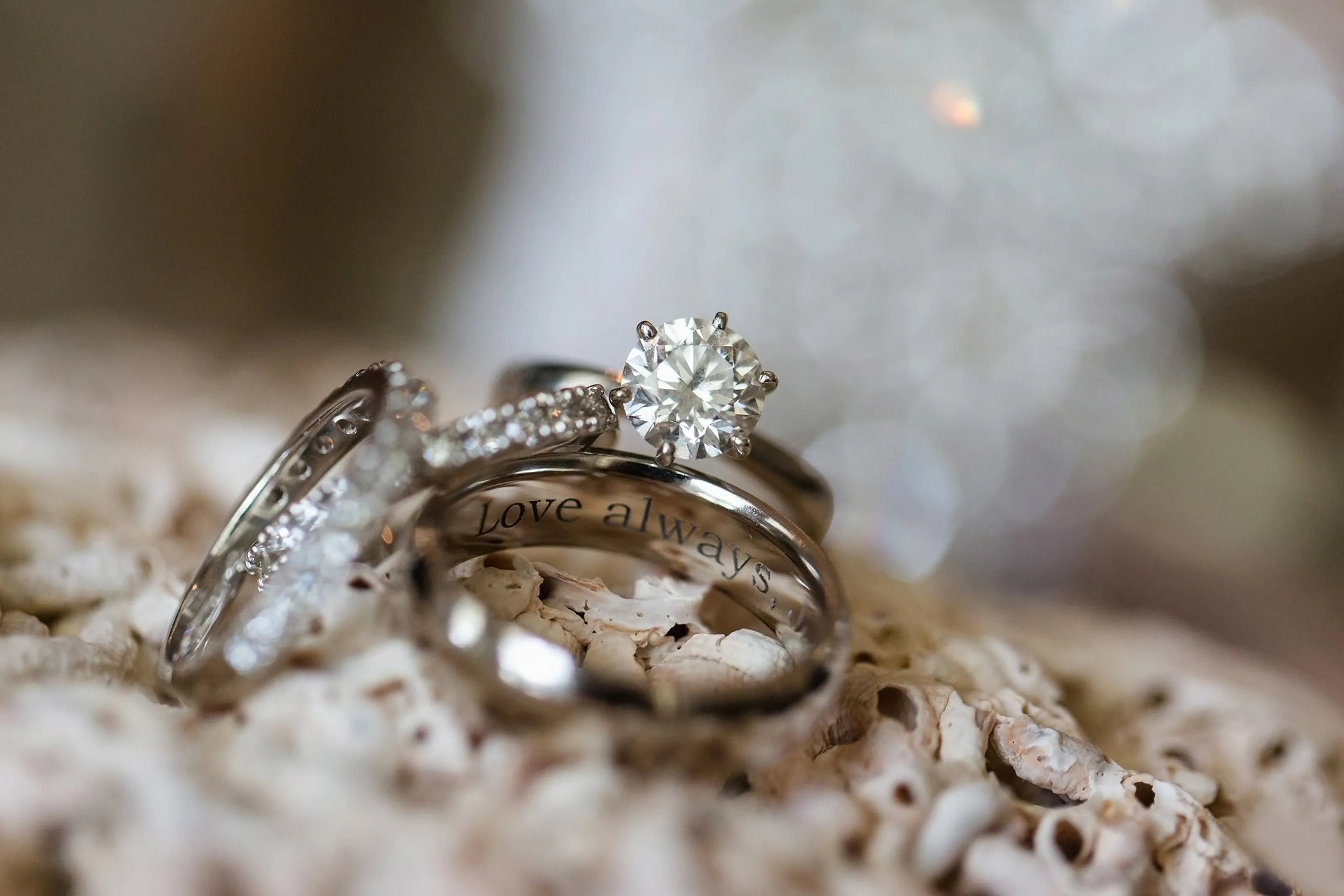 Close-up of three wedding rings with a diamond centerpiece, inscribed with 