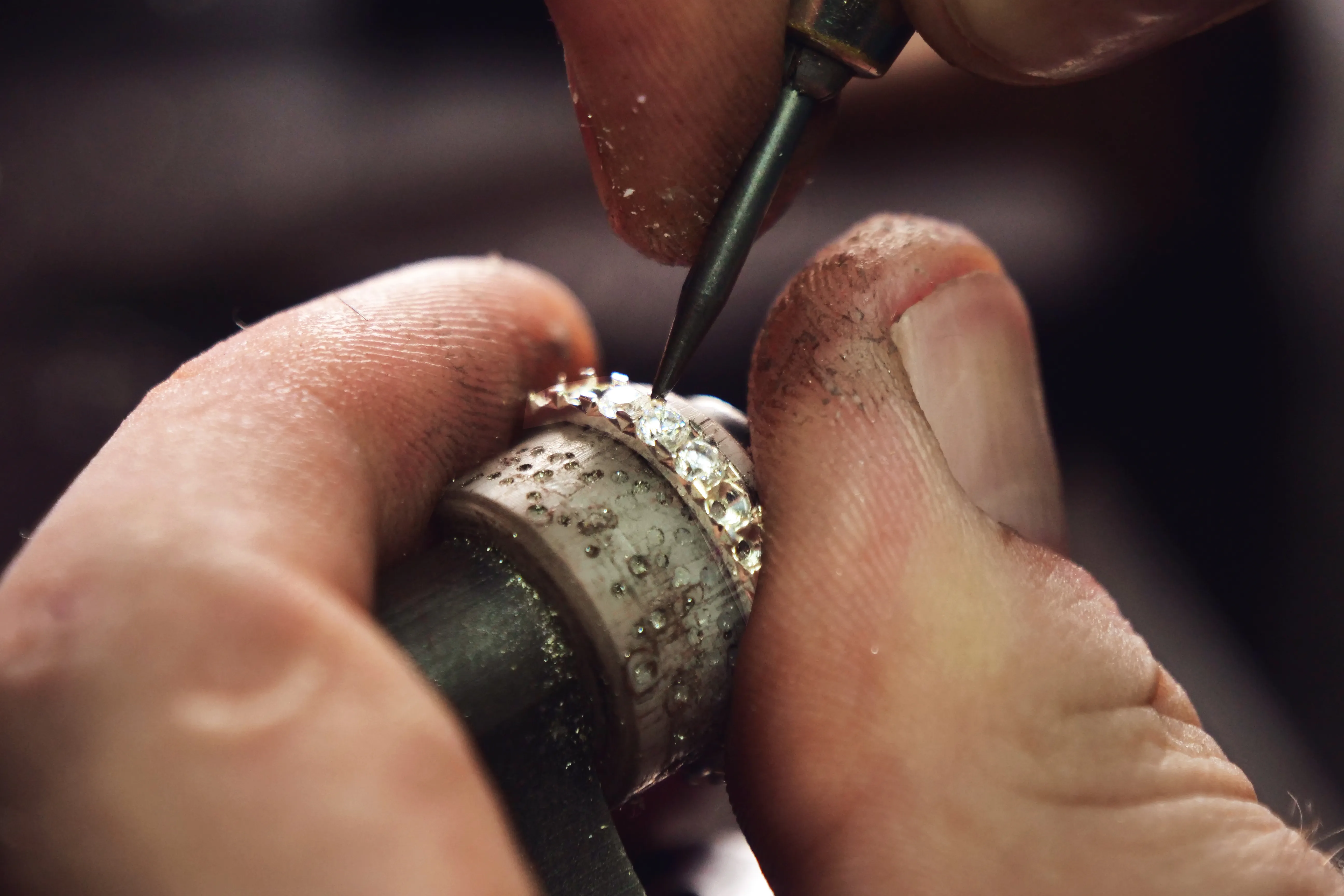 Jeweler meticulously setting stones on a ring, showcasing craftsmanship at Monarch Jewelry in Winter Park.