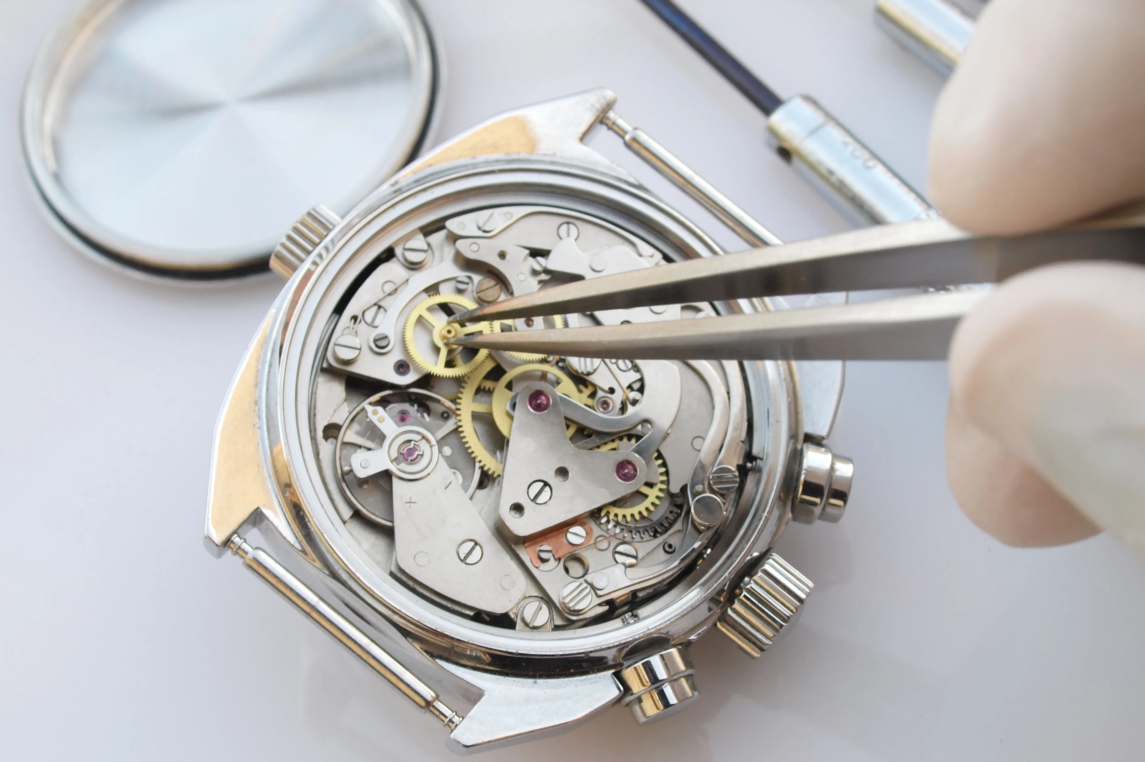 Close-up of a watch mechanism being repaired with tweezers, showcasing intricate gears and components.