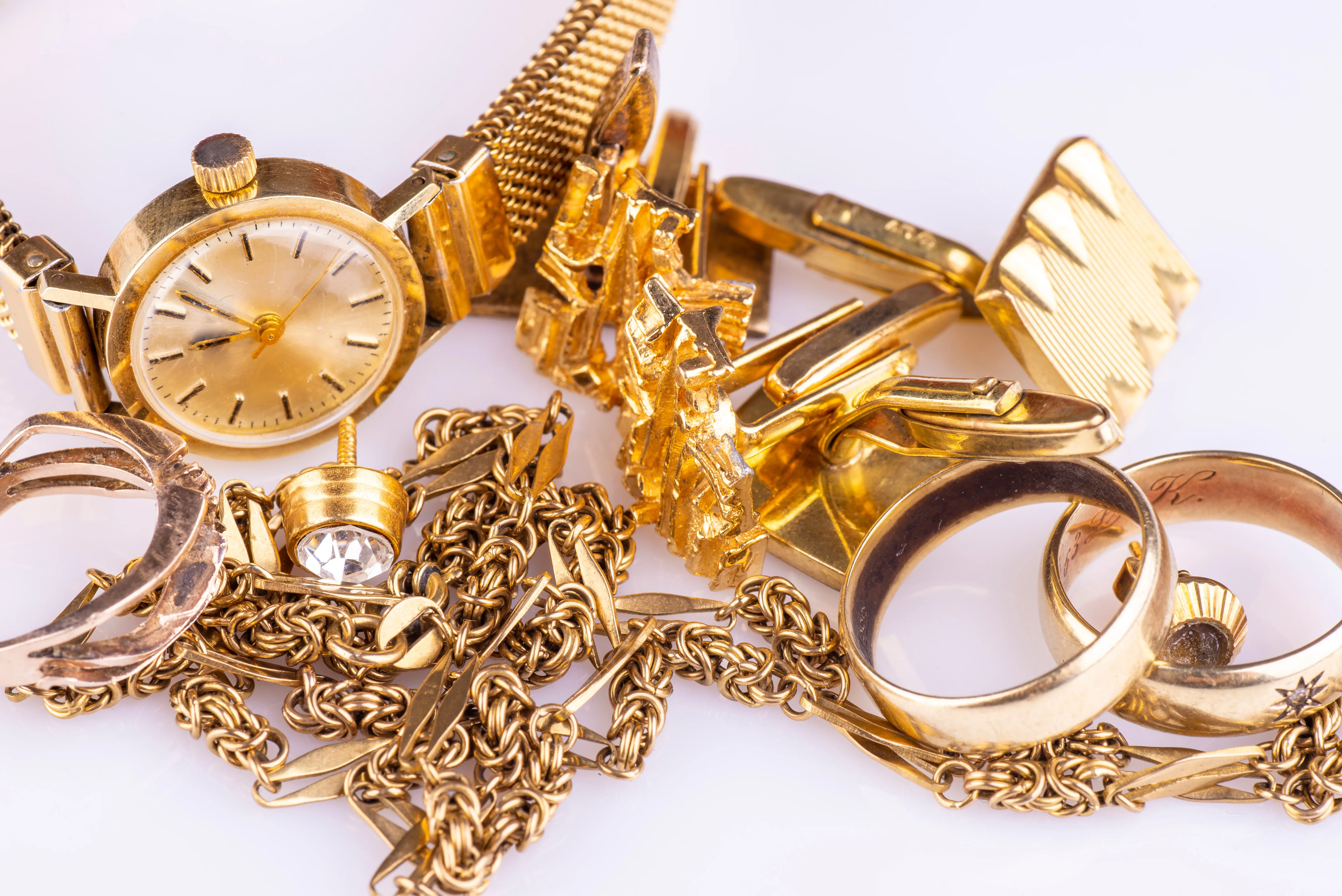 Gold jewelry collection including a watch, rings, and chains. Visit Monarch Jewelry in Winter Park for fine pieces.