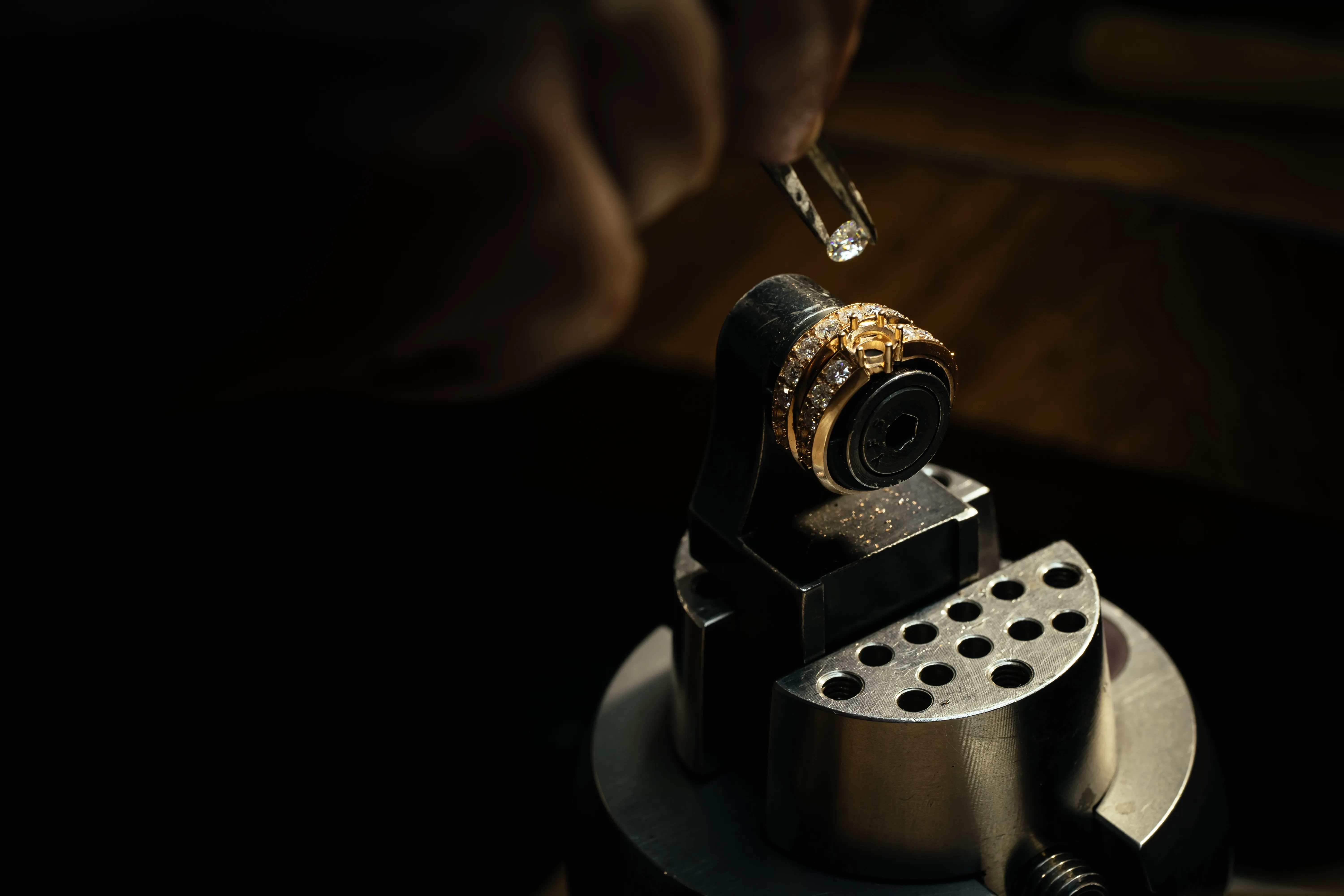 Jewelry repair in progress, featuring a gold ring and a diamond being set at Monarch Jewelry in Winter Park. Contact Us.