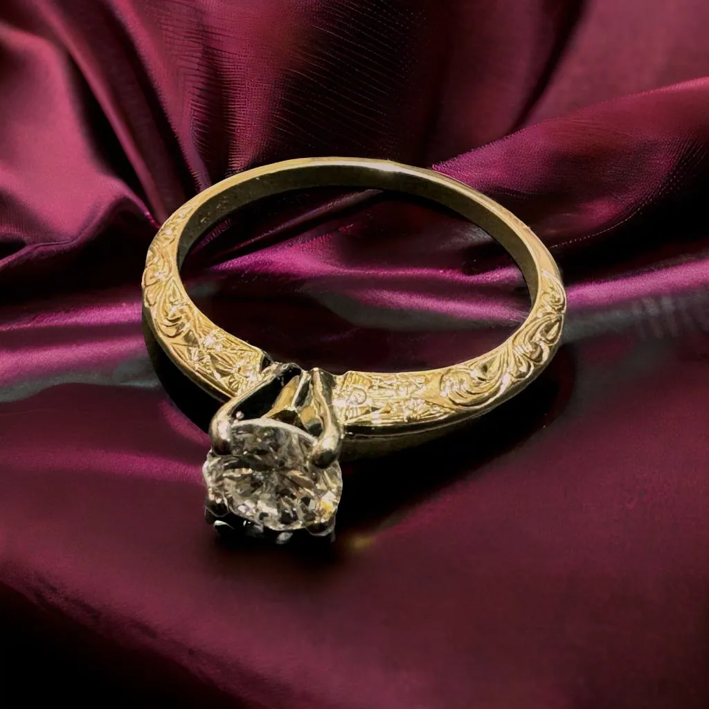 Elegant gold engagement ring with a large diamond, resting on rich burgundy fabric. Visit Monarch Jewelry in Winter Park.