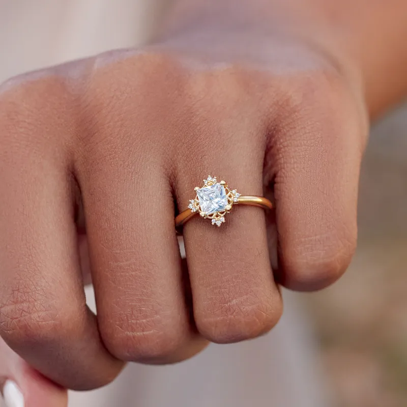 Elegant gold ring with a square stone and diamond accents, worn on a hand. Shop at Monarch Jewelry in Winter Park.