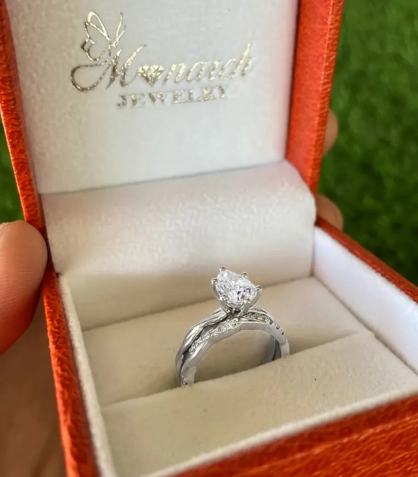 Elegant engagement ring in a Monarch Jewelry box, featuring a pear-shaped diamond and intricate band design.