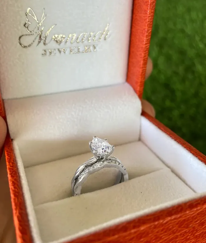 Elegant engagement ring in a Monarch Jewelry box, featuring a pear-shaped diamond and intricate band design.