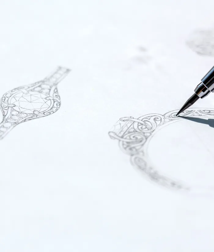 Detailed sketch of an ornate ring design with a pen, showcasing custom jewelry artistry. Click to start a project.
