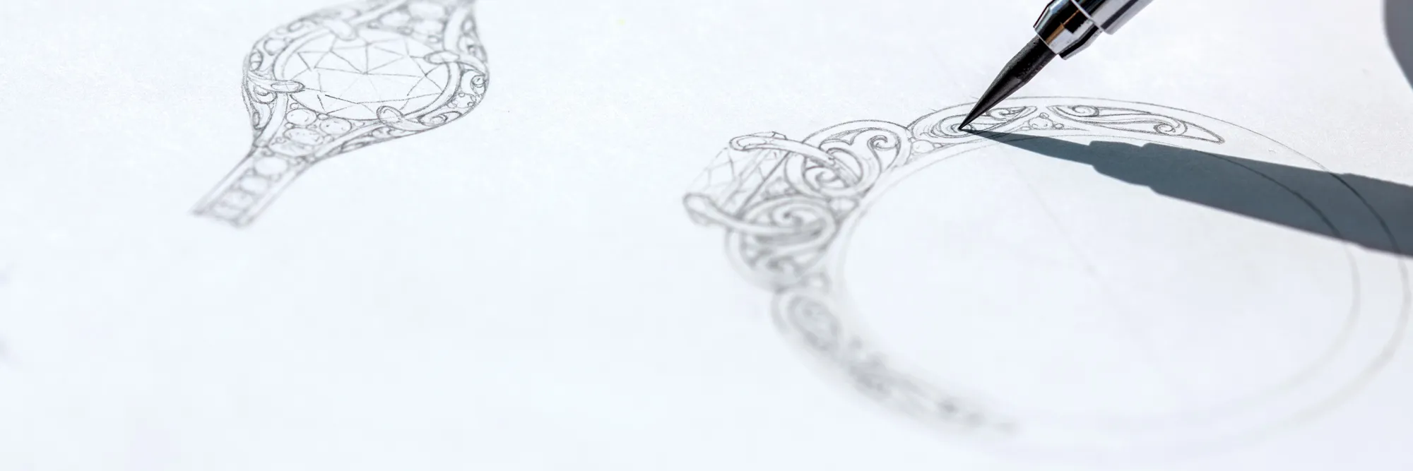 Detailed sketch of an ornate ring design with a pen, showcasing custom jewelry artistry. Click to start a project.